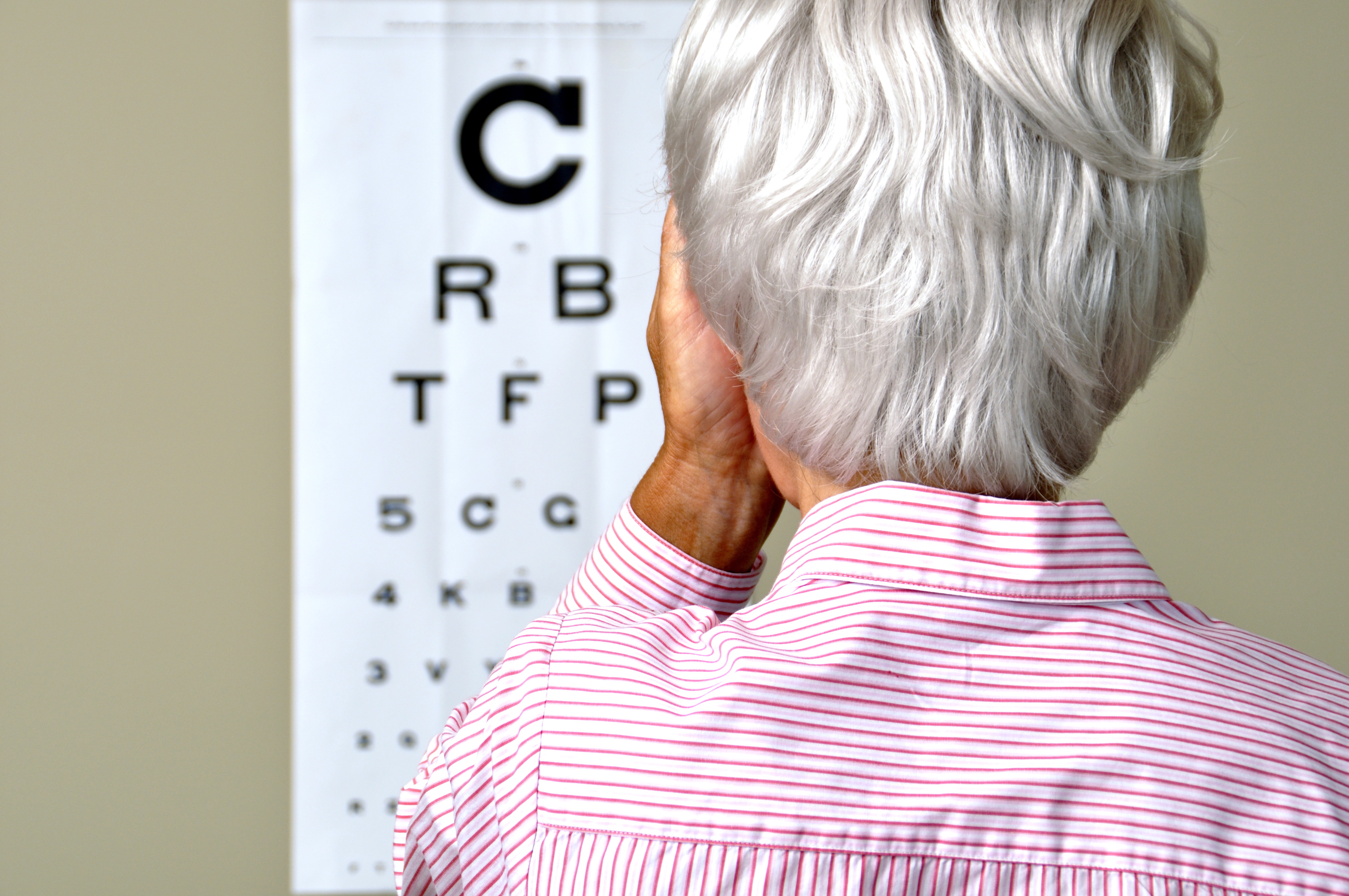 Older woman covering one eye and looking at letters on vision test chart